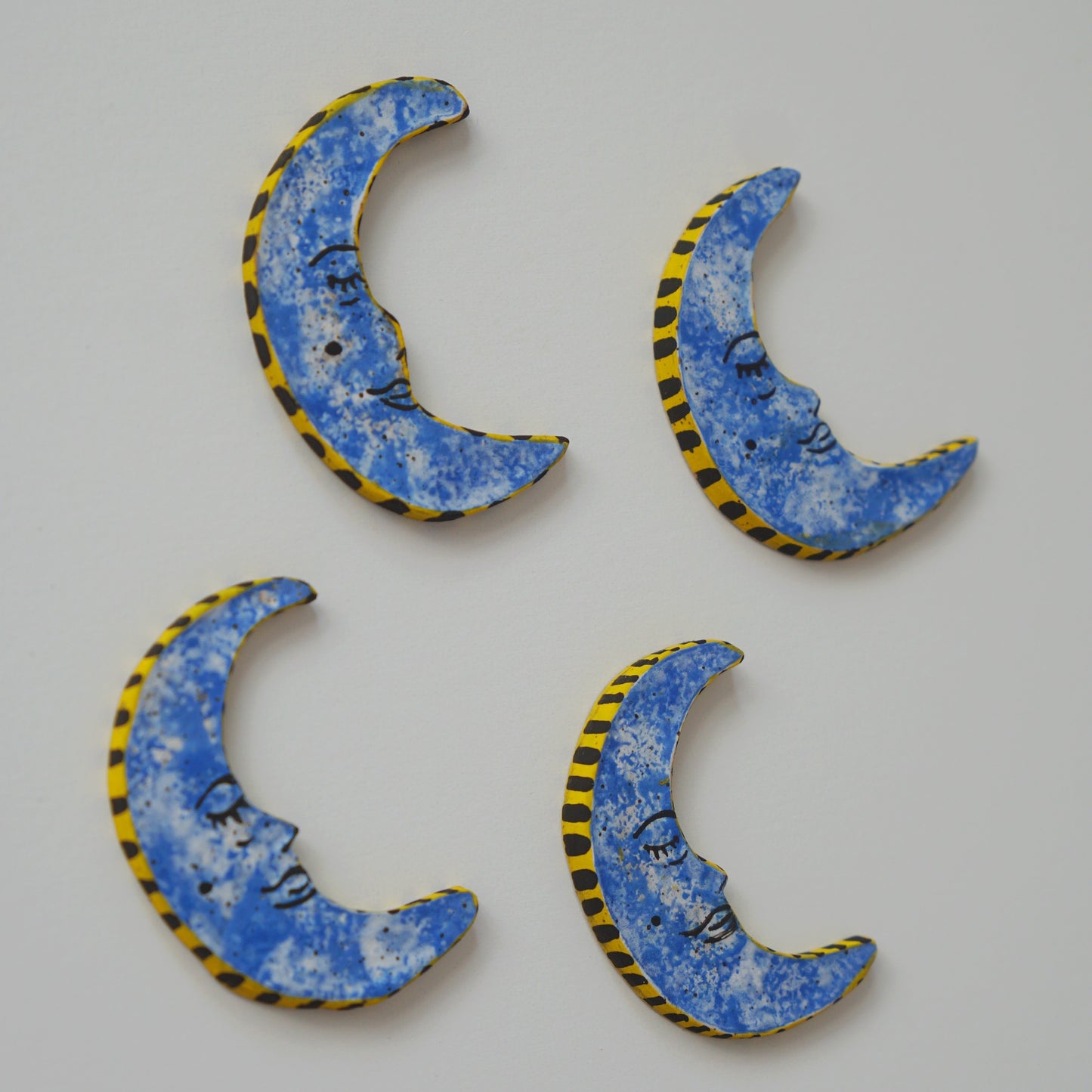 Four blue crescent moon-shaped objects with yellow and black borders on a light gray background