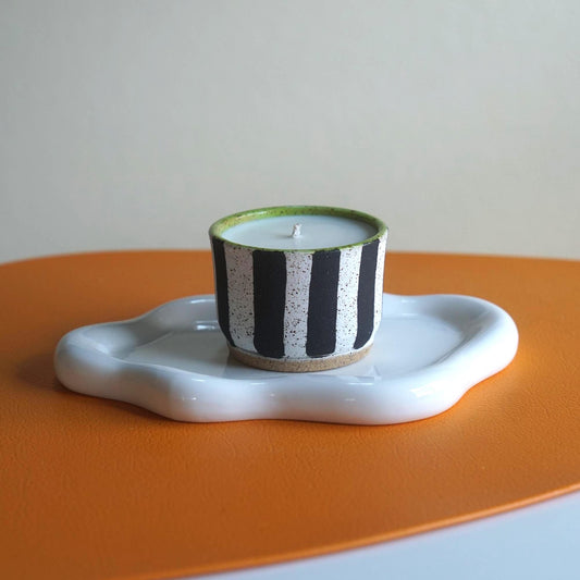 Ceramic candle holder with striped design on an orange surface