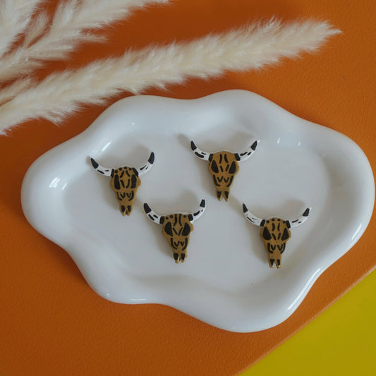 Four bull skull longhorn figurines on a white dish with a colorful background