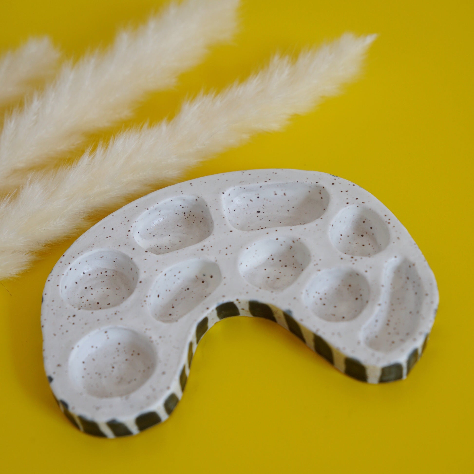 Ceramic paint palette with black accents on a yellow background