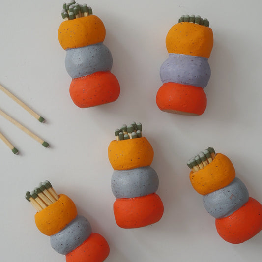 Matchstick holders with orange, gray, and red colors on a white background