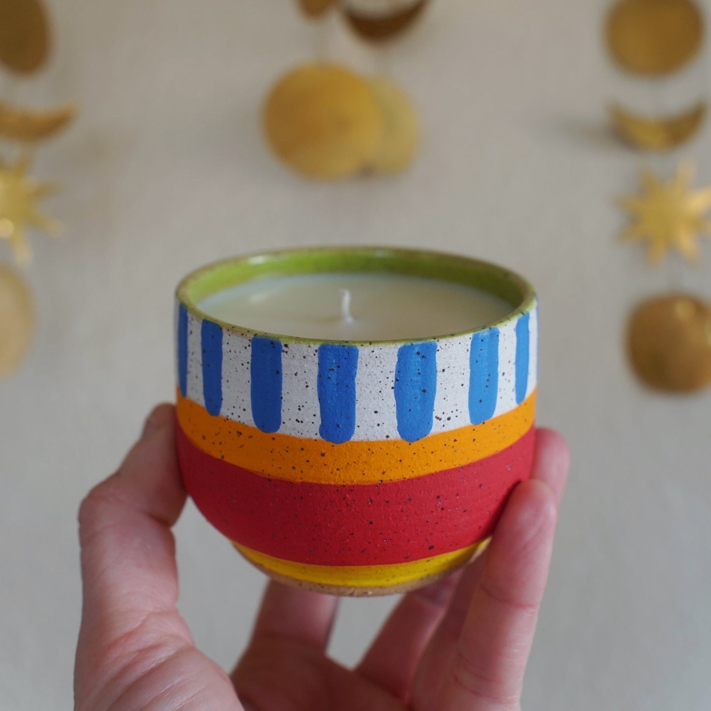 Hand holding a striped candle with decorative background