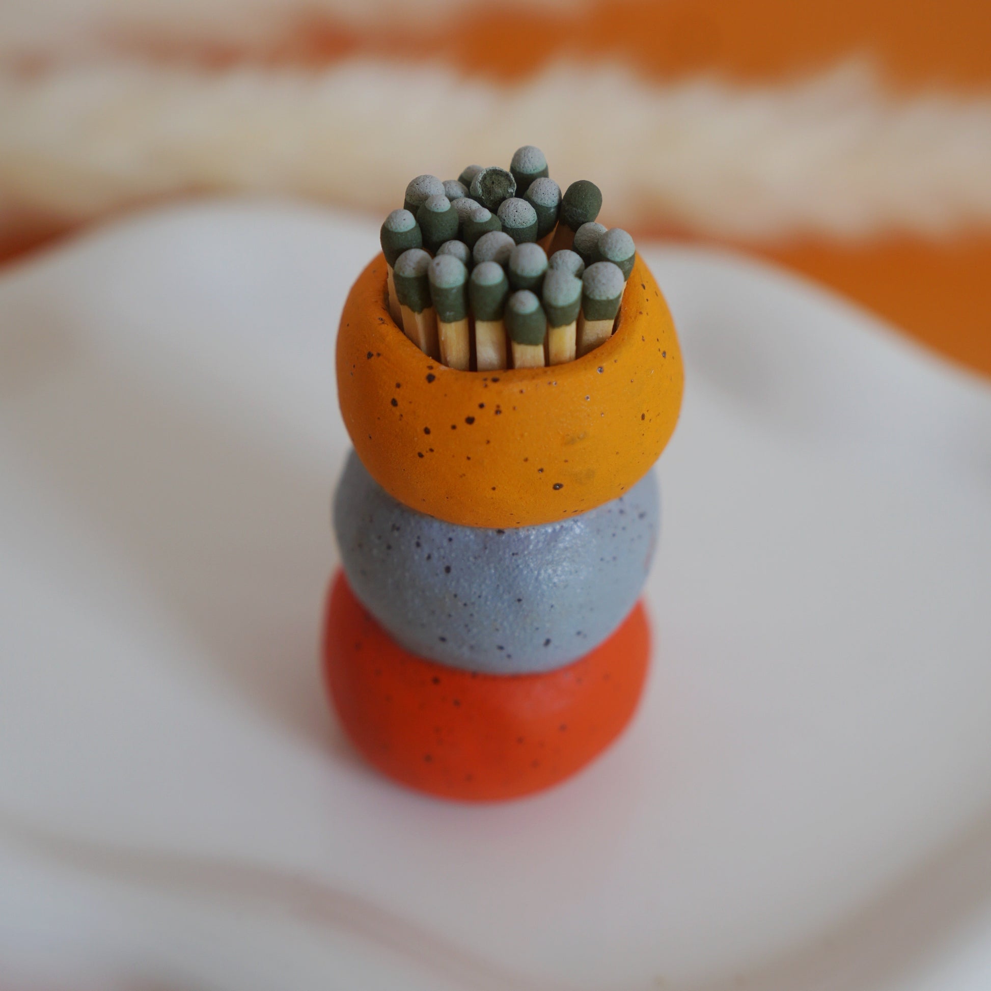 Stack of colorful matchsticks on a white and orange surface