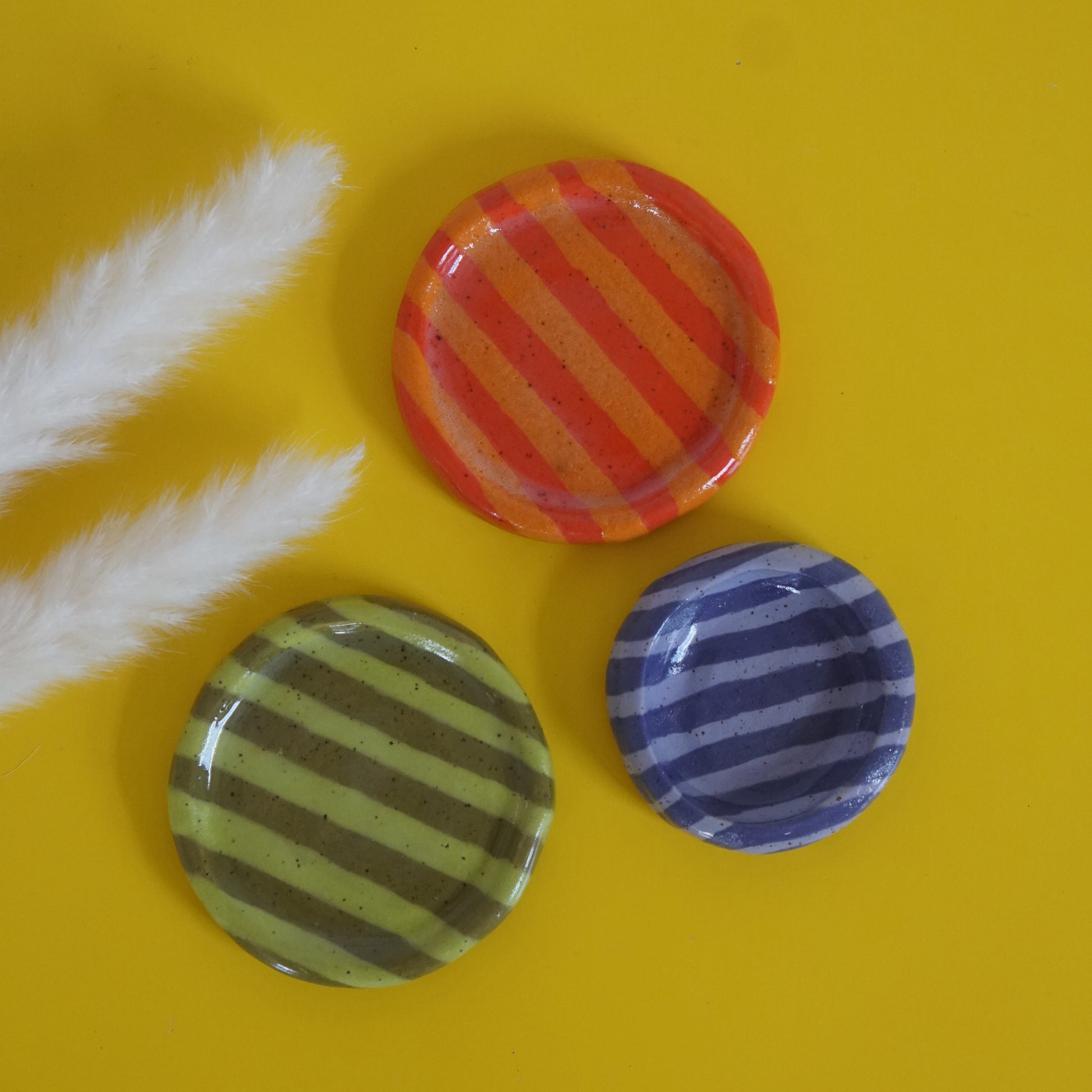 Three striped ceramic ring dishes on a yellow background