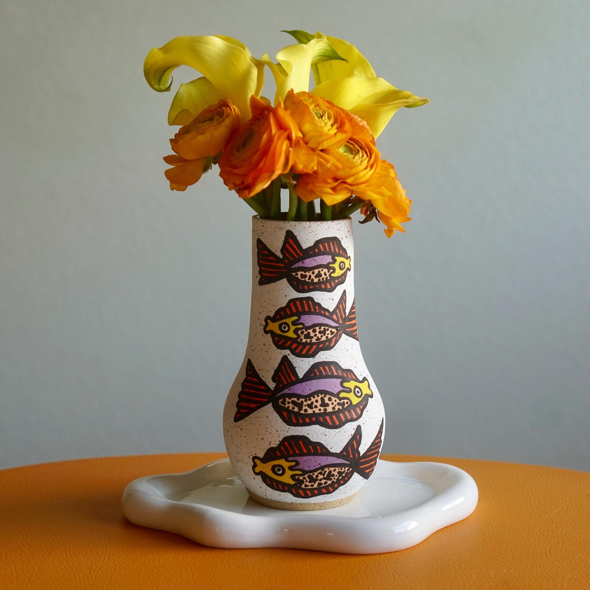 Decorative vase with fish patterns holding flowers on a table