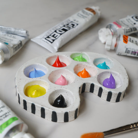 Artistic palette with colorful paint samples and open paint tubes on a light surface
