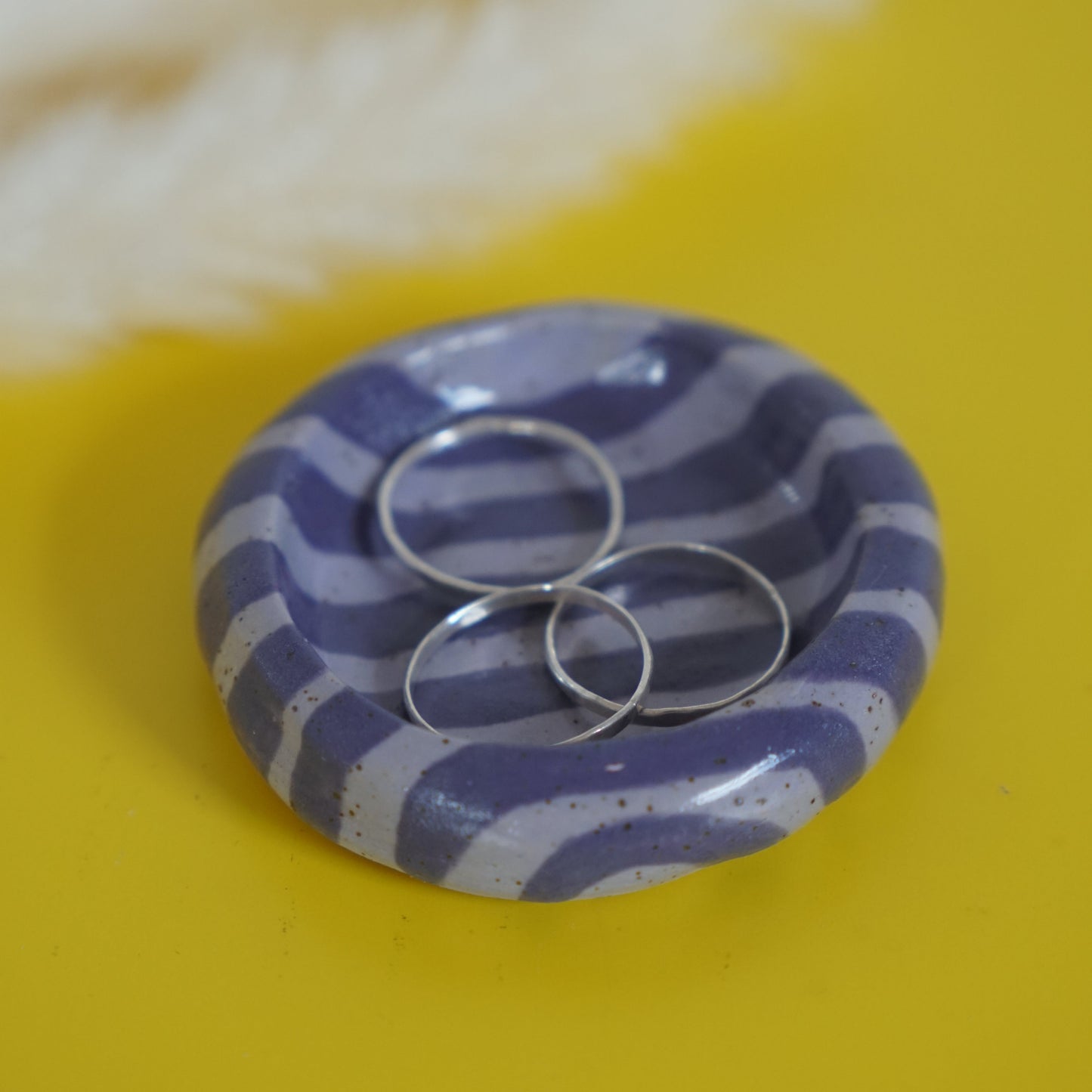 Purple striped ring holder with two rings on a yellow background