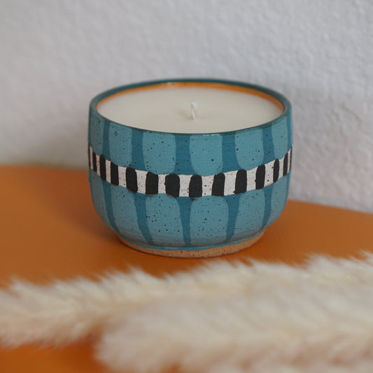 Ceramic candle holder with striped design on an orange surface